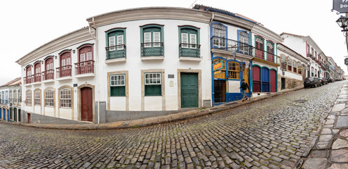 Super wide view of steep wet cobblestone road passing the typical historic colonial colourful house...