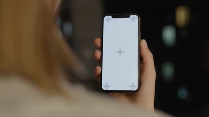 Woman uses smartphone with green white screen chroma key with track points at modern room stays near the window with great night view watching content videos blogs close up view slow motion