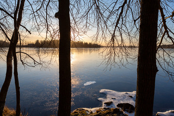 Wintry landscape from Finland during February. Cold afternoon sunset scenery. Frozen lake shore.