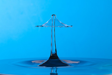 Abstract photograph of a water drop collision created with two water drops splashing together isolated against a blue background.