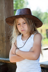 Deeply offended young girl, dressed cowboy leather hat and white shirt, crossed arms, purse lips