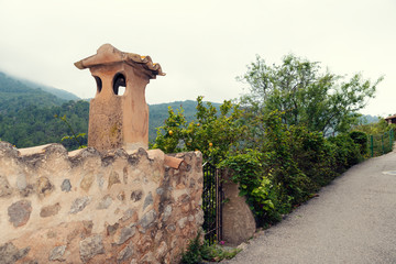 Romantic narrow street with stone fence and chimney in mediterranean village in island Majorca Selective focus