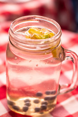 Fresh tropical beverage served in a jar made with ice and delicious fruits on a plaid tablecloth