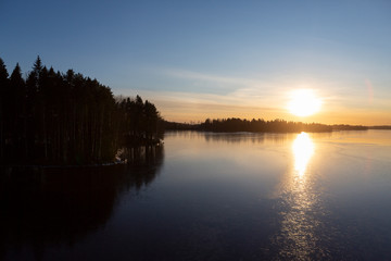 Wintry landscape during sunset in Finland. Cold afternoon in February. Golden hour and reflecting ice and water on the shore.