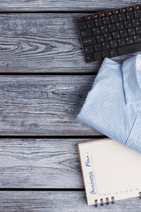 Keyboard, shirt and planner. Office items on wooden background close up. Minimalism concept.