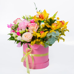 Flower arrangement in a hat box, a pot of pink for a girl on a gift with roses, orchids. Bouquet of beautiful flowers in the cylinder pink box isolated on white background