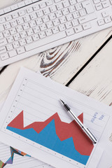 Keyboard with documents and pen above. Graphic and digits. Analyst's workplace.