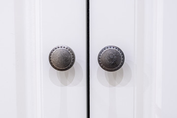 Metal round handles on a white half-open door, close-up