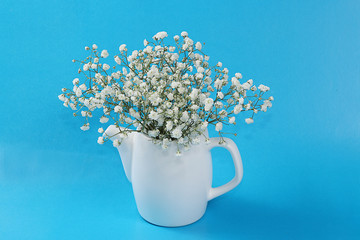 Bouquet of flowers in a mug on a blue table, abstract spring floral background. Creative modern bouquet, minimal holiday concept. Greeting card for Women's Day or Mother's Day, happy birthday,