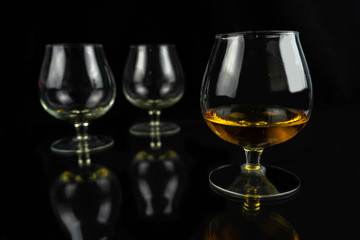 Three whiskey / cognac glasses on a black dark background