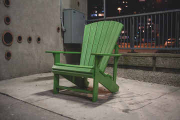 Fototapeta na wymiar Green Muskoka Chair in park during Night Time in the Winter Weather