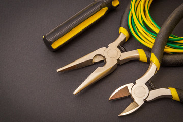 Electrician's tools and wire on black background for repairing energized systems or communications