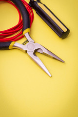 Electrician's tools and wire on yellow background for repairing energized systems or communications