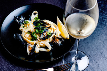 Blue mussels and pasta in black plate