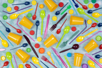  Disposable single use plastic objects such as cups, forks and spoons and drinking straws on blue background, top view