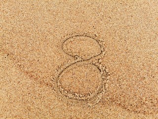 Fototapeta na wymiar The number 8 on wet beach sand. 