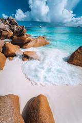 Foam wave between rocks on Grand Anse beach, La Digue, Seychelles. White clouds, crystal clear...