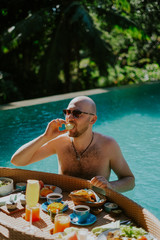 Man having breakfast in the pool in Ubud, Bali