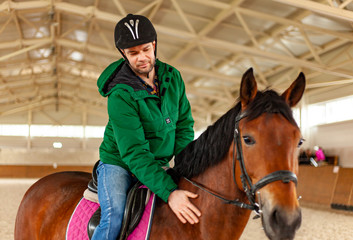 man jockey sitting on horse, horseback training on manege, lesson for jockey in equestrian school...