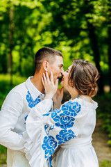 Ukrainian wedding in traditional embroideries. Lovely newlyweds walking in the park