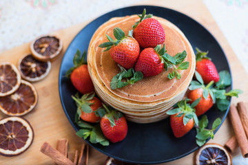 Brunch, favorite morning meal. Homemade berry  pancakes, fresh summer dessert with strawberries on wooden table, close up, selective focus.