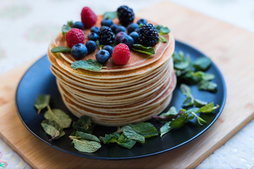 Stack of pancakes. Pancakes with berries. Raspberries and blueberries. Classic Russian dessert. The holiday of Maslenitsa.