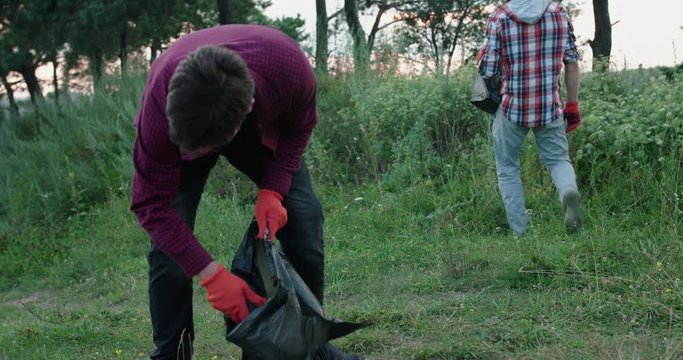 View of young man collects the plastic lied around the nature