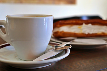 cup of coffee with milk and cake with cream in coffee shop