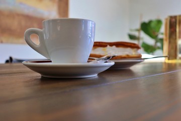 cup of coffee with milk and cake with cream in coffee shop