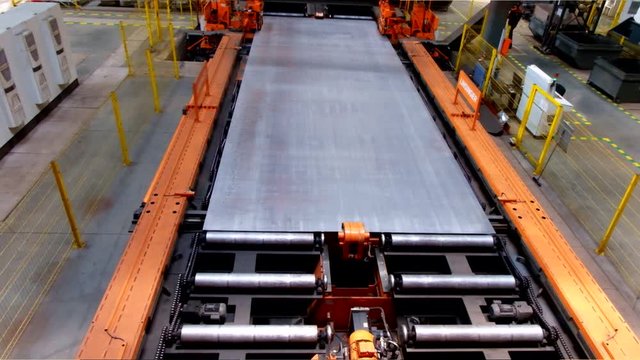 Steel sheet moving on roller conveyor in metalworking workshop