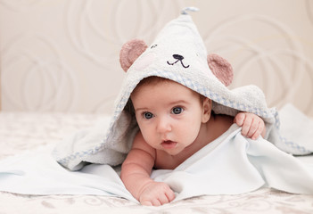 baby boy lies on his stomach in a towel with ears after bathing