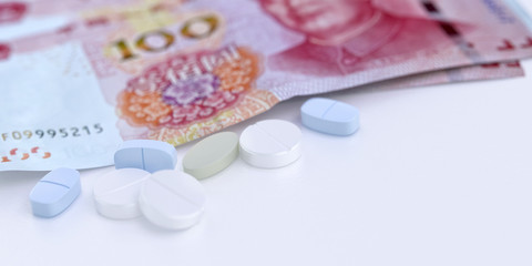 Pharmaceutical medicine pills tablets, China 100 Yuan banknotes close up 3D illustration. China pandemic pathogen coronavirus covid-19 outbrake, increased costs for ncov corona virus disease concept