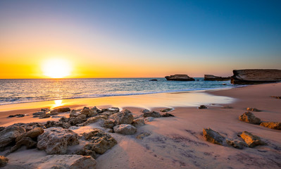 Swirl pattern of a wave rolling onto beach at sunset time
