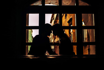 Fototapeta na wymiar Silhouettes of two lovers on a window background in a cozy cafe. .Restaurant overlooking the old street