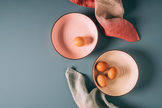 Overhead still life shot of farm fresh eggs on pastel plates with ombre napkins