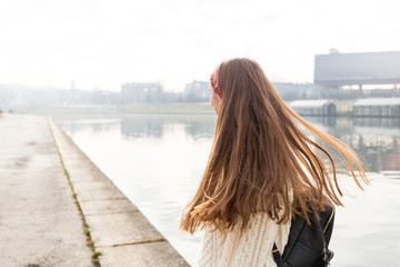 Young teenage girl on river background. Outdoor photo of happy young woman, she looks into the distance