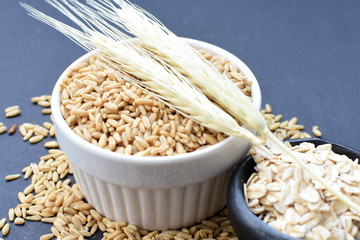 Oat grains and flakes, accompanied by wheat ears in containers for display