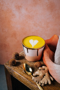Golden milk latte in pink and gold cup with tumeric and ginger