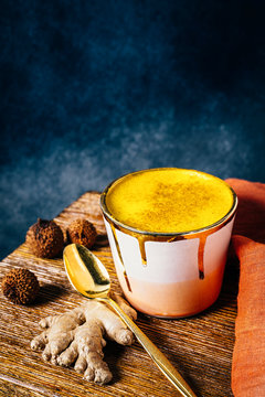 Golden milk latte in pink and gold cup with tumeric and ginger