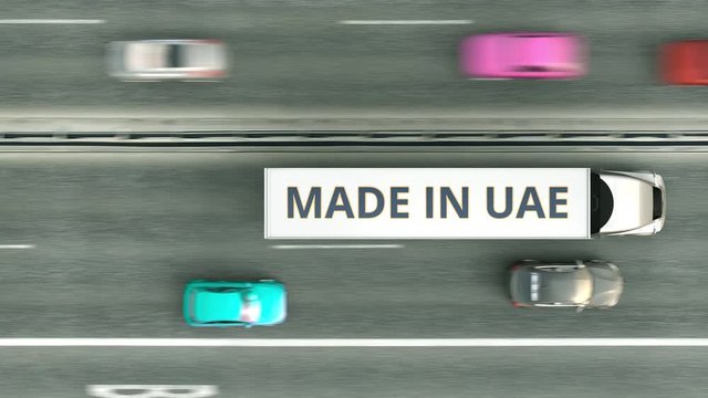 Aerial overhead view of trailer trucks with MADE IN UAE text driving along the highway. United Arab Emirates business related loopable 3D animation