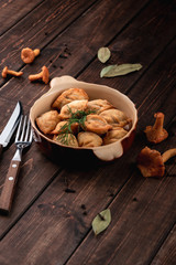 Russian traditional meal homemade dumplings stuffed with chanterelle mushrooms in a bowl on a dark wooden background, national cuisine concept, side view