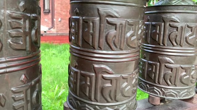 Rotating nepalese traditional metal prayer wheels with mantra Om Mani Padme Hum, that means O, the jewel in the lotus, hanging in a row