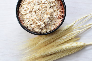 Oat grains and flakes accompanied by wheat ears in containers for display