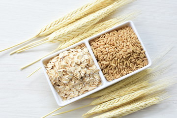 Oat grains and flakes accompanied by wheat ears in containers for display