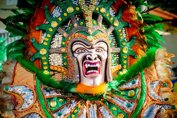 closeup man in varicolored mask and costume poses at camera on dominican carnival