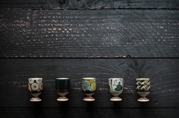 set of antique sake glasses, rice, and sake bottle with blank space on dark wooden table, mockup, copyspace, copy space, japanese rice wine