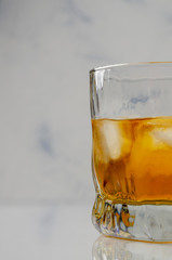 Whiskey or whisky in glass from with reflection white background