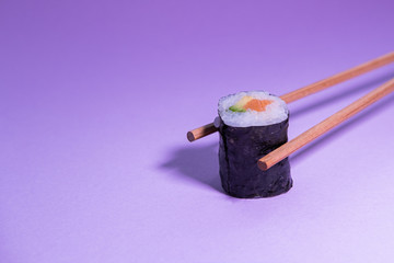 Chopsticks taking salmon and avocado maki sushi. Concept photography. Japanese food.