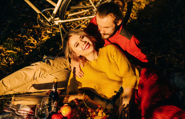 Autumn couple picnic at sunset. Rest in the park on the mat for two