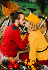 Amazing couple kissing while sitting on carpet in park on bicycle background. Autumn picnic with...